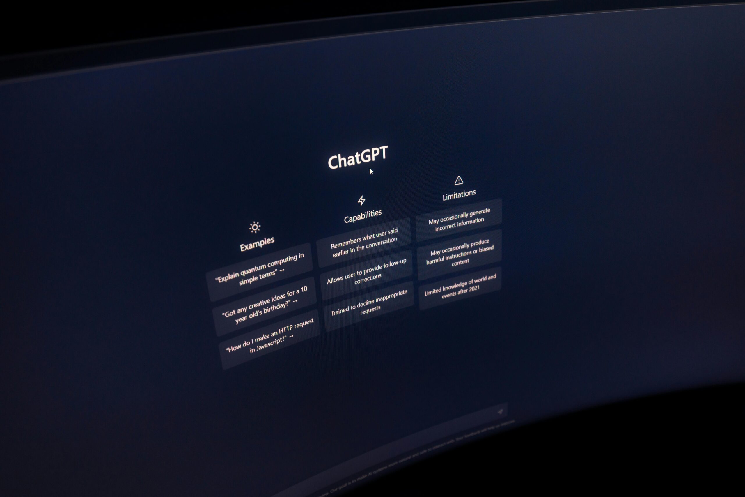 Pantalla curva mostrando la interfaz de ChatGPT con sus capacidades, ejemplos y limitaciones — los modelos frontera como sistema operativo central.
